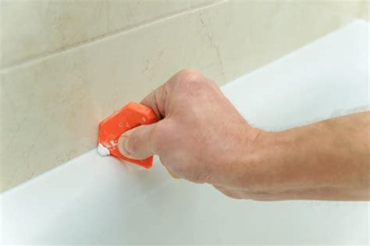 How do you apply silicone sealant to a shower tray?
